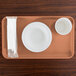 A dark peach rectangular Cambro tray with a white bowl and cup on it.