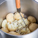 A bowl of potatoes with a Thunder Group Chrome Plated Square-Faced Potato Masher with a wood handle.