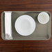 A rectangular taupe Cambro tray with a bowl, plate, and cup on it.