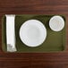 A rectangular olive green Cambro tray with a white plate and cup on it.