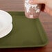 A hand holding a cup over a Cambro tray with a plate on it.