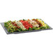 A Tablecraft granite rectangular platter with a salad topped with lettuce, tomatoes, and other vegetables.