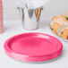 A stack of hot magenta pink paper plates on a white background.