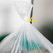 A plastic bag with a yellow ribbon tied to it using Bedford Industries Inc. yellow laminated twist tie.