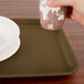 A hand holding a cup over a Bay Leaf Brown Cambro tray.