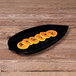 An Elite Global Solutions black melamine platter with sliced papaya on it.