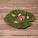 A green leaf shaped melamine platter with pink flowers on it.