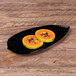 An Elite Global Solutions black melamine platter with papaya slices and mango.