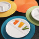 A close-up of an Elite Global Solutions white melamine plate with four compartments filled with sliced peppers.