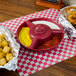 A red tray with a bowl of raspberry sauce and a plate of fries with a yellow bowl of tater tots on it.