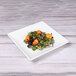 An Elite Global Solutions white square melamine tray with a salad on it.