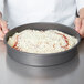 An American Metalcraft hard coat anodized aluminum cake pan with a pizza inside.