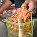 A person using a Cambro amber plastic colander pan to hold bacon.