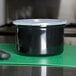 A Carlisle black plastic crock with lid on a green cutting board.