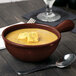 A Tablecraft maroon speckle cast aluminum soup bowl with croutons and a spoon on a table.