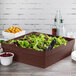A brown Tablecraft square bowl filled with salad on a table.