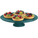 A hunter green Tablecraft cake stand with fruit on it.