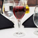 A close-up of a Chef & Sommelier Exalt wine glass filled with red wine on a table.
