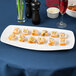 A Tuxton white rectangular china plate with sushi on a table.