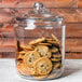 An Anchor Hocking glass jar full of chocolate chip cookies on a counter.