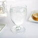 An Arcoroc banquet goblet filled with water and ice on a table with bread.