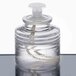 A clear glass container with a white lid filled with clear liquid.