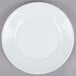 An Arcoroc white glass side plate with a white rim on a gray surface.
