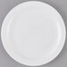 An Arcoroc white opal glass lunch plate with a white rim on a gray surface.