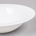 An Arcoroc white opal grapefruit bowl with a white rim on a gray surface.