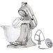 A KitchenAid mixer with a glass bowl and whisk attachment.