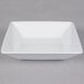 A Tuxton TuxTrendz bright white square china bowl with a handle.