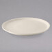 A close-up of a Tuxton eggshell china pizza plate with a rim on a gray surface.