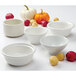 A group of Tuxton white mini round china bowls filled with red and white potatoes.