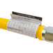 A stainless steel Dormont gas connector hose with a yellow label.