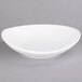 A Tuxton white oval china bowl on a gray surface.