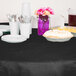 A table with a Creative Converting black velvet table cover, plates, and cups.