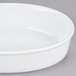 A white oval deep dish porcelain serving platter on a gray surface.