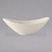 A close-up of a Tuxton oval eggshell white china bowl with a curved edge.