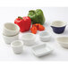 A variety of Tuxton white China ramekins on a table with a green bell pepper.