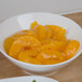 A bowl of peaches in a yellow sauce.