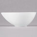 An Arcoroc white porcelain deep bowl with a curved edge on a gray background.