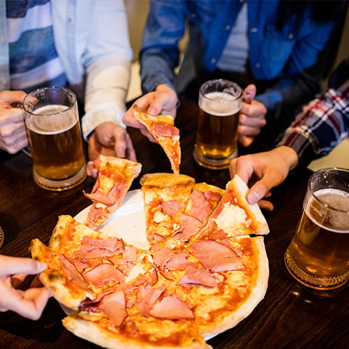 Friends drinking beer with pizza