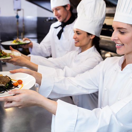 three chefs passing plated food