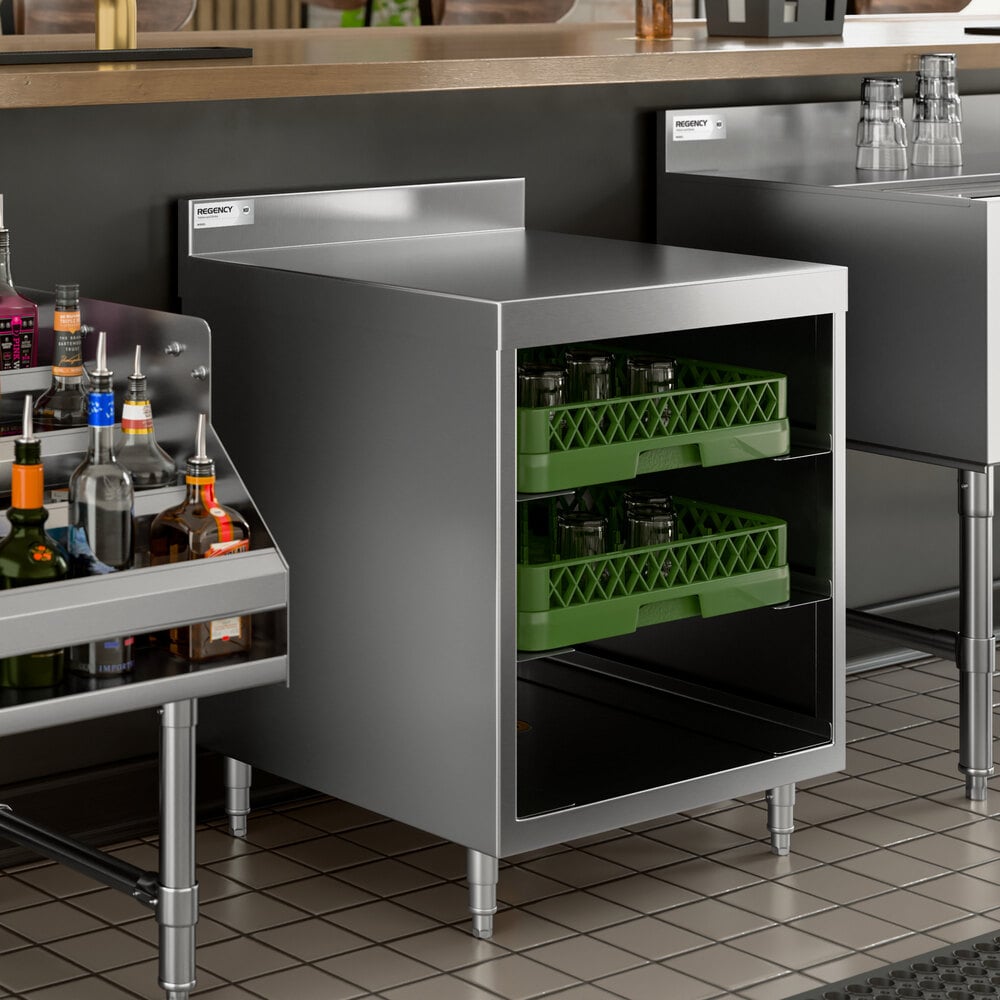 A stainless steel storage unit with two shelves holding green glass racks, situated under a countertop in a bar or kitchen setting.