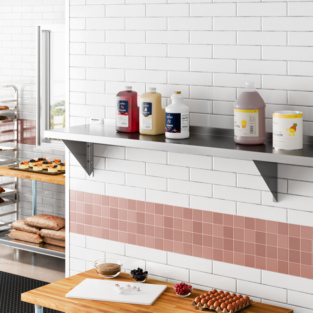 A long, heavy-duty stainless steel wall shelf mounted on a tiled kitchen wall, holding various large containers.