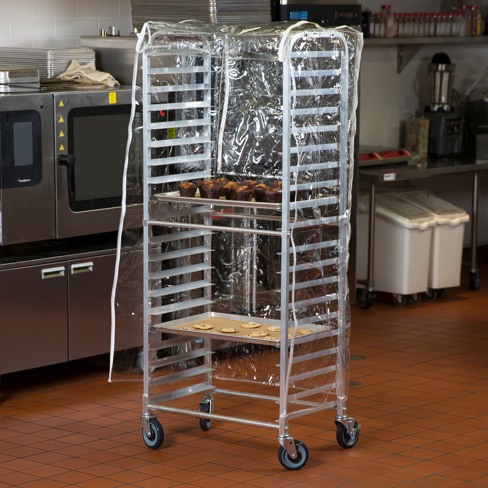 A clear plastic bun pan rack cover fitted over a tall metal rack in a commercial kitchen.
