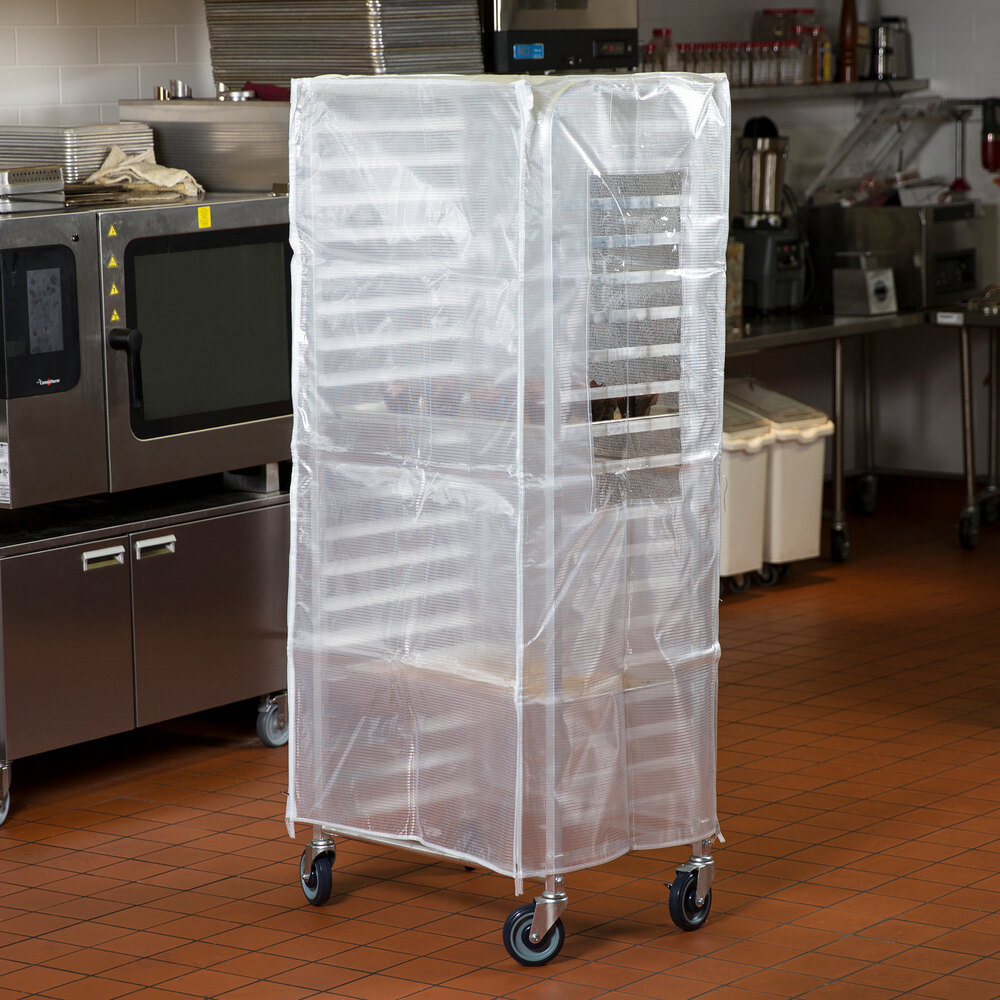 A translucent plastic bun pan rack cover fitted over a tall rack in a commercial kitchen.