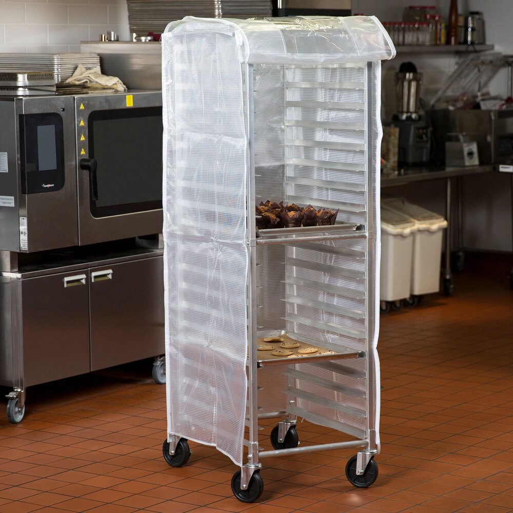 A translucent plastic bun pan rack cover fitted over a tall metal rack in a commercial kitchen.
