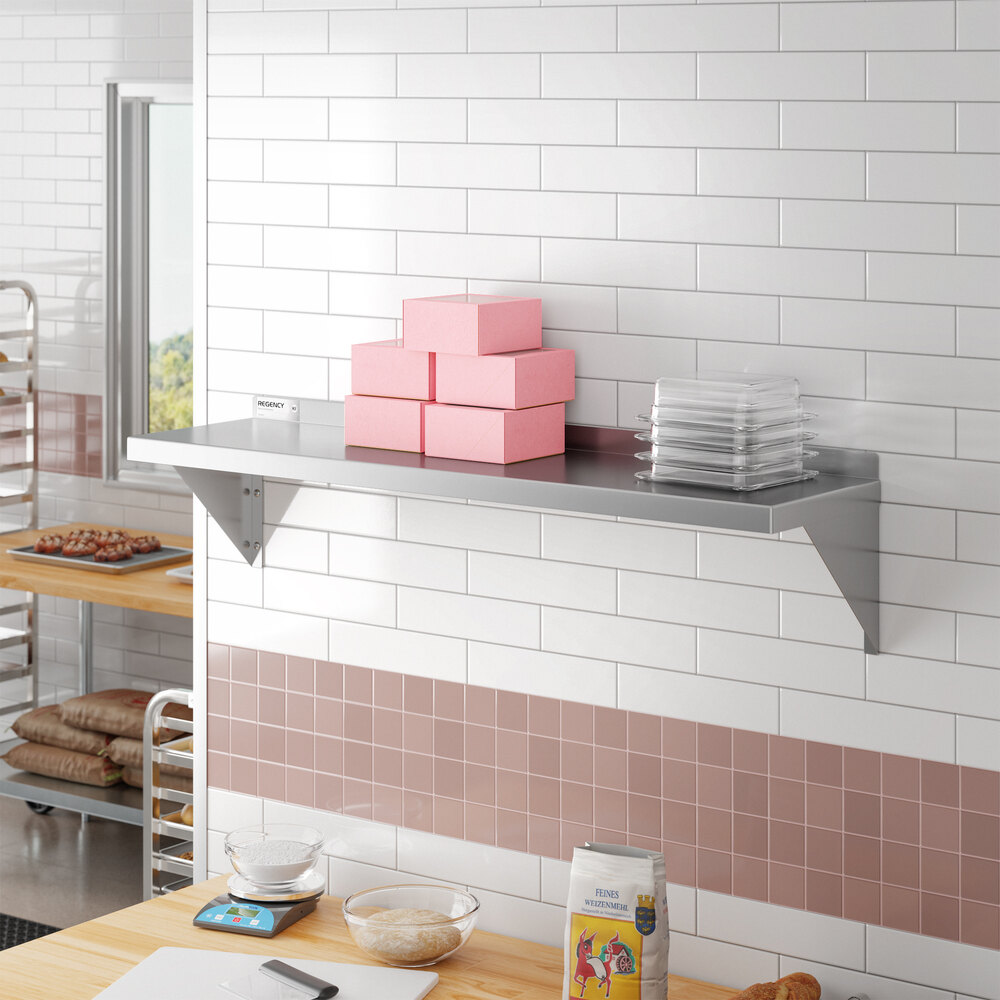 A stainless steel 12-inch by 48-inch solid wall shelf mounted on a tiled kitchen wall.