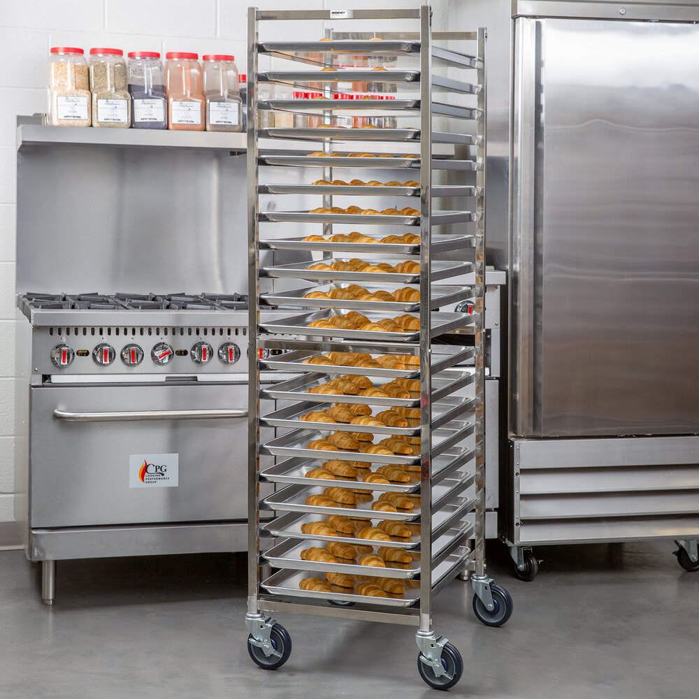 A tall, stainless steel rack on wheels holds multiple trays of baked goods in a commercial kitchen setting.